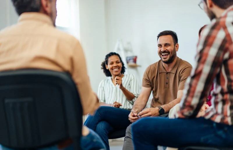 An adult man, looking happy, talking with random people from the group therapy. | Amarillo Medical Specialists Rheumatology